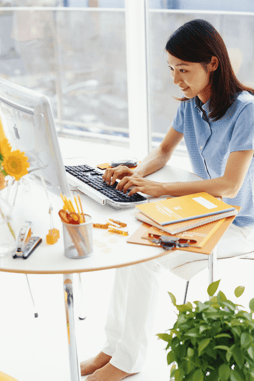 Woman sitting at desk, working on desktop computer 
