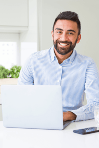 Seated man smiling while working on laptop